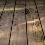 Low-profile wooden deck by SC Projects LLC with brown composite railings and lattice skirting surrounded by decorative river rock .