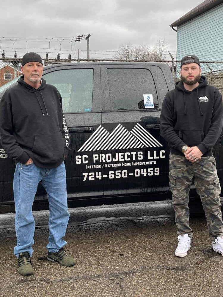 Members of SC Projects LLC standing in front of a black company truck with the logo and contact information.
