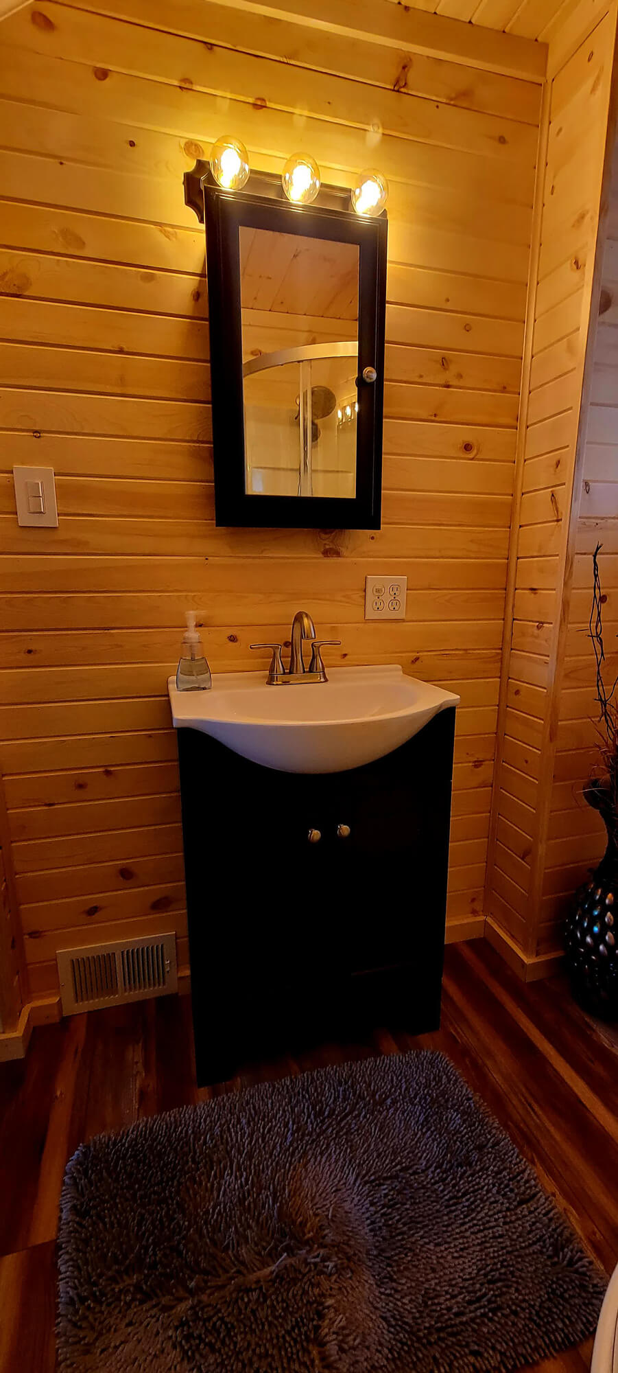Sleek, modern bathroom remodel by SC Projects LLC featuring a walk-in shower with glass doors, a gray vanity, and light gray wood-look plank flooring.
