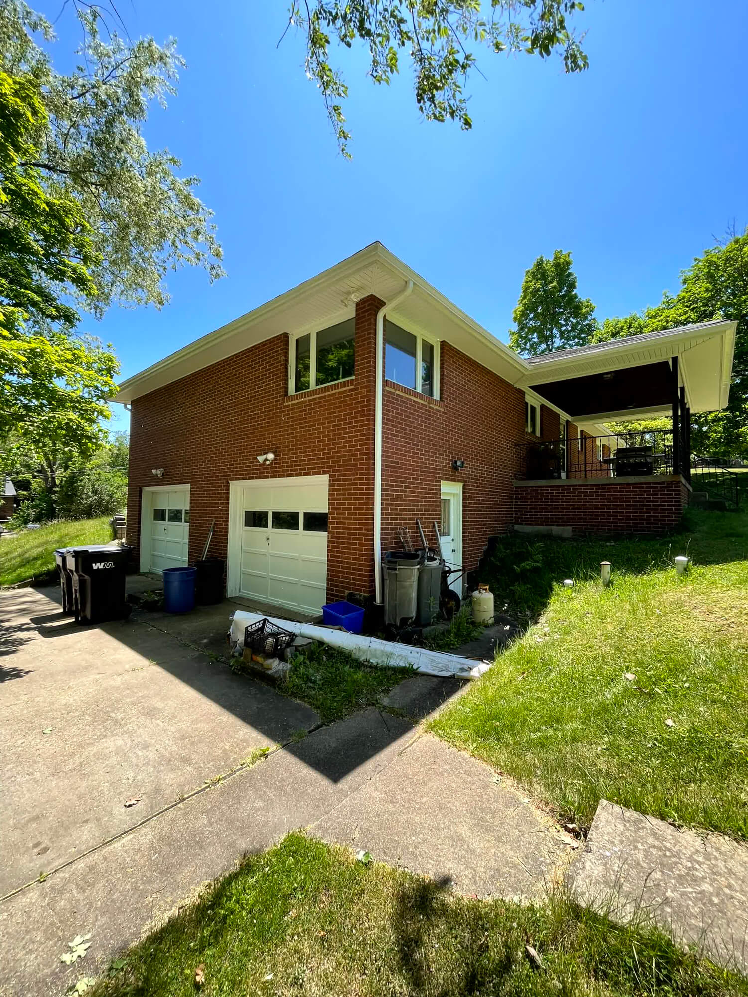 The exterior of this red brick home shows multiple white garage doors and a newly installed white gutter system, maintained by a skilled contractor in Beaver County, PA .