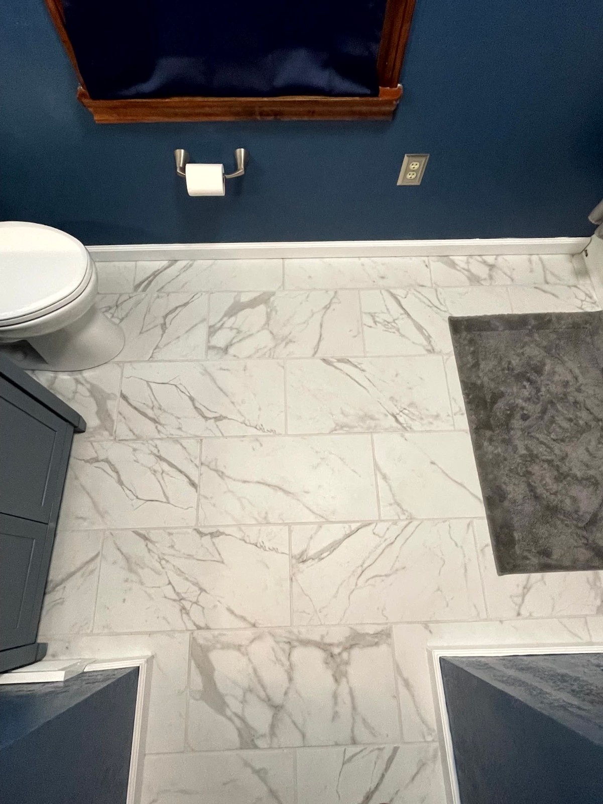 A contemporary entryway with gold geometric wallpaper, navy blue wainscoting, and a wooden coat rack, showcasing stylish interior remodeling by a contractor