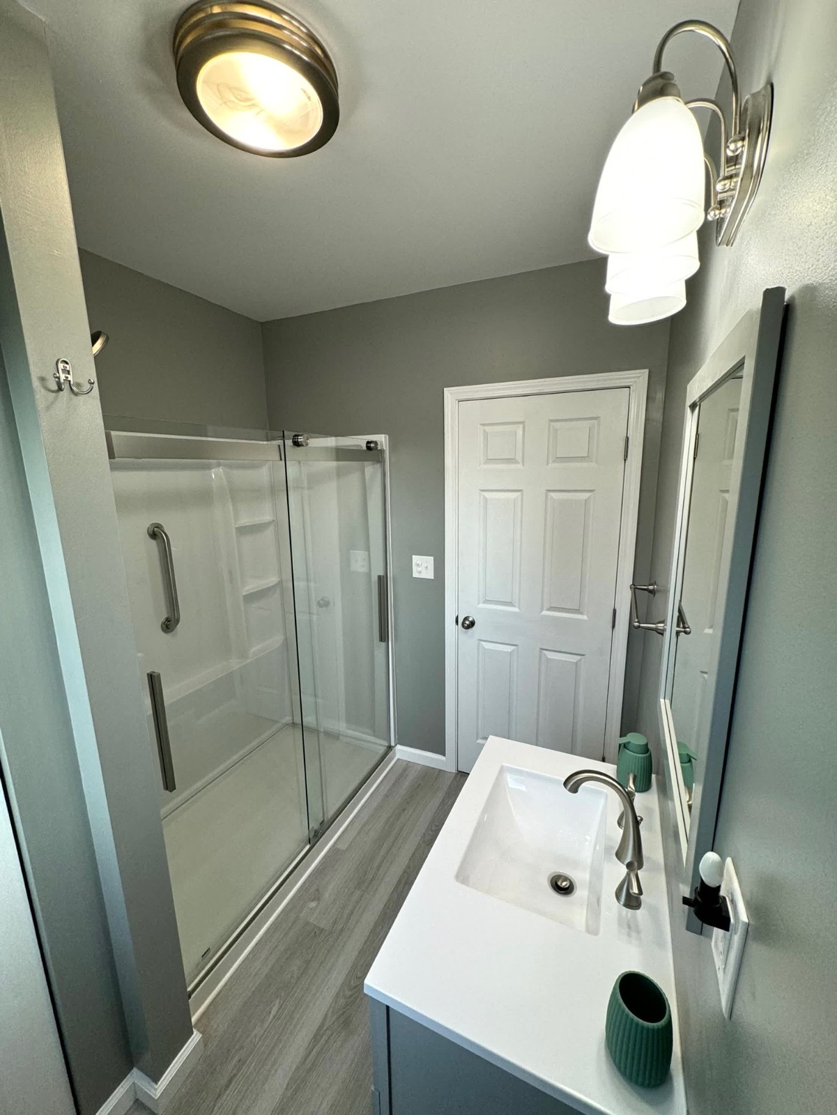 Walk-in shower with white rectangular marble-look tiles, a gray mosaic accent border, a rain showerhead, and a white hexagon mosaic shower floor.