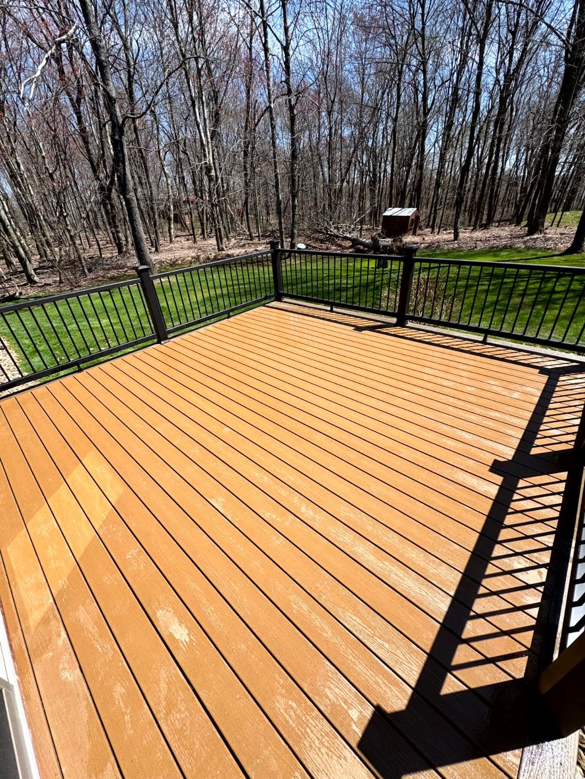 Elevated composite deck structure installed by SC Projects LLC with brown horizontal slat skirting and a hidden access door underneath .