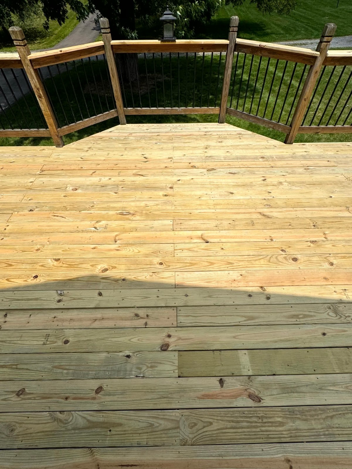 Finished treated wooden deck with traditional wood railing and black metal balusters installed by SC Projects LLC .