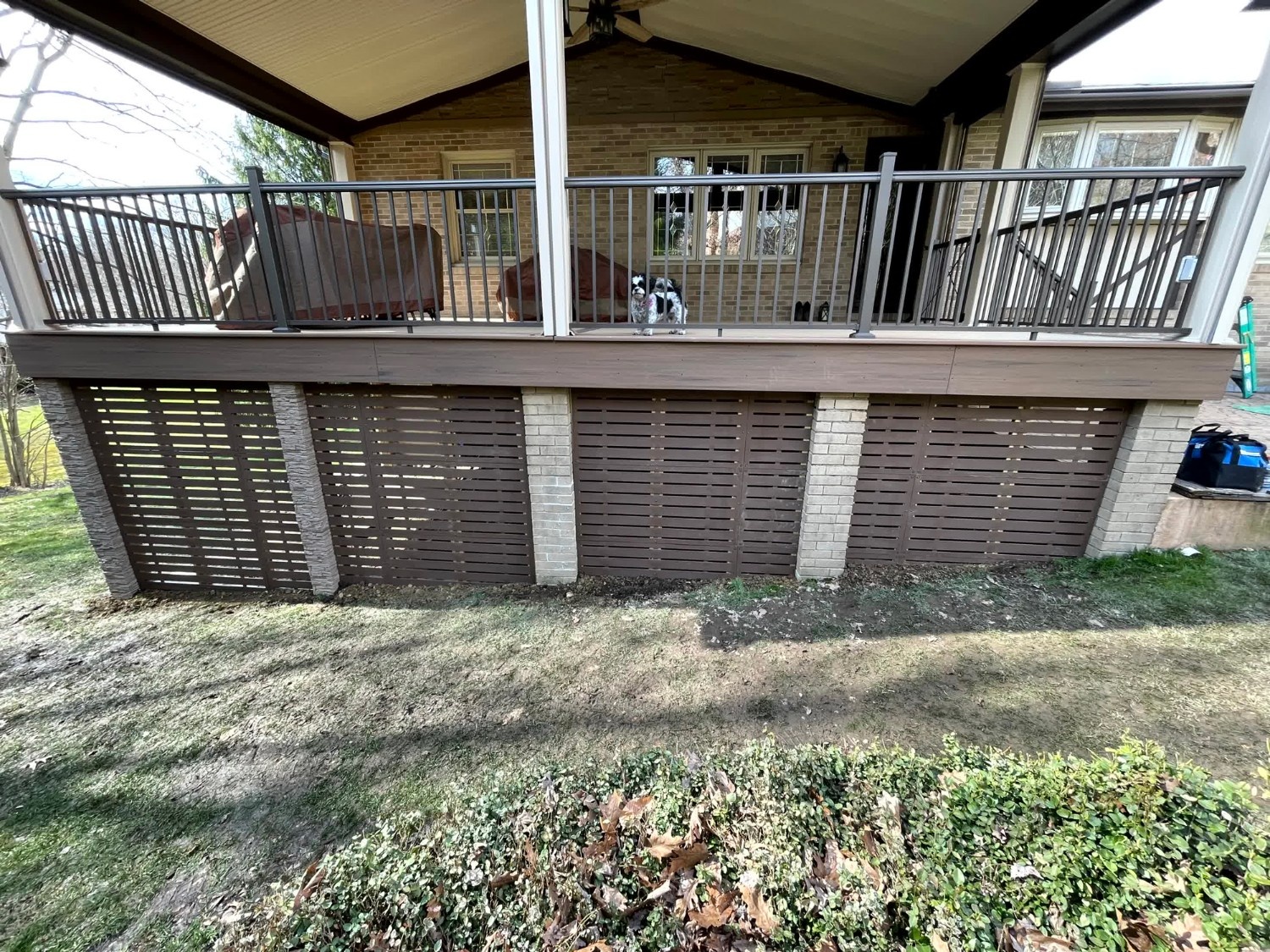 Large wooden deck with built-in bench seating and pressure-treated lumber installed by SC Projects LLC backed by a wooded area .