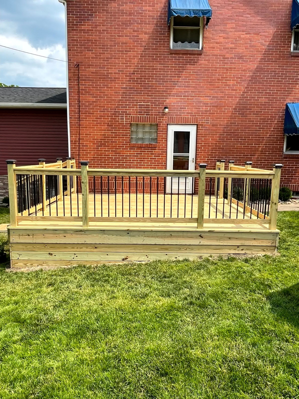 SC Projects LLC sign advertising general contracting and free estimates on a suburban lawn in front of a finished red brick deck installation .