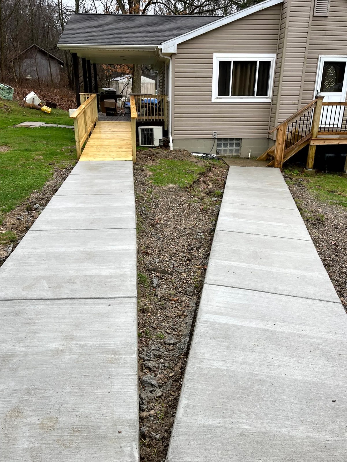 New construction of a wooden deck built by SC Projects LLC with stairs and wood railings attached to a modern stucco home .