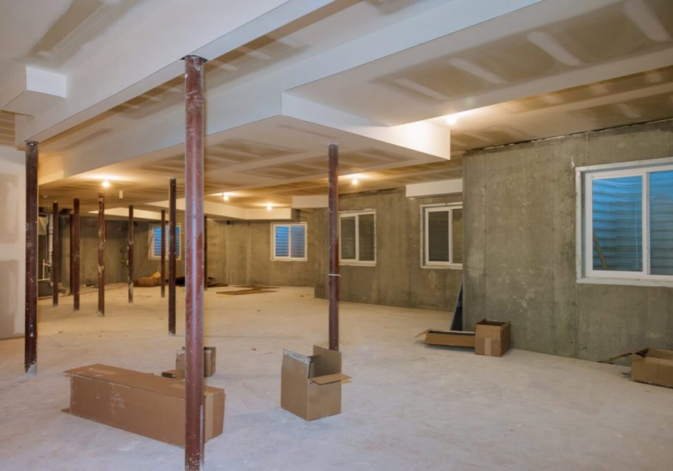 Basement remodeling project by SC Projects LLC showing exposed support columns, new drywall ceiling, and egress windows prior to finishing .